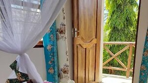 Una habitación con suelo estampado, una puerta de madera y vistas al exterior con vegetación.