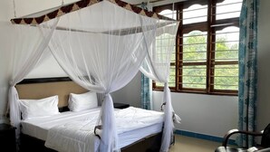Una cama con dosel, una silla y una ventana con cortinas.
