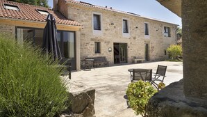 A stone building with a tiled roof, outdoor seating, and a stone pillar. - Landras de Compostela (Santiago de Compostela)
