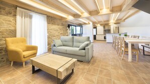 A spacious living area with a sofa, a coffee table, and a dining table with chairs. A kitchen is visible in the background. - Landras de Compostela (Santiago de Compostela)