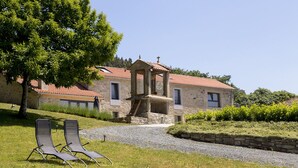 A stone building with a red-tiled roof, a balcony, and two lounge chairs in the foreground. - Landras de Compostela (Santiago de Compostela)