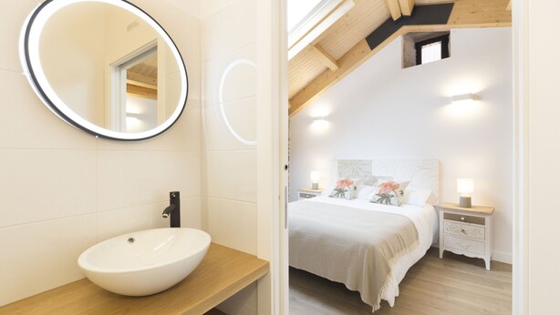A modern bathroom with a round mirror, a white sink, and a wooden vanity. - Landras de Compostela (Santiago de Compostela)