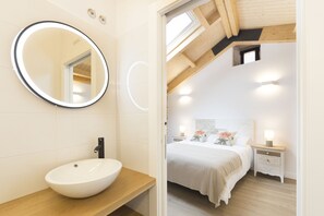 A modern bathroom with a round mirror, a white sink, and a wooden vanity.