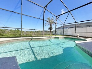 A clear blue pool surrounded by a metal fence, with a palm tree and a wooden fence in the background. - Sweet Magnolia - Kissimmee pool home overlooking conservation (Kissimmee)