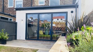 Une maison moderne dotée d’une grande porte vitrée donnant sur un patio.