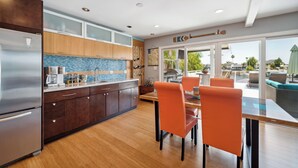 Een moderne keuken met houten kastjes, een roestvrijstalen koelkast en een eethoek met oranje stoelen.
