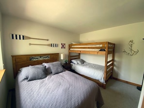 Un dormitorio con una cama individual, una cama nido, un cabecero de madera, un remo sujeto a la pared y un cartel que dice 'NO WAKE ZONE'.