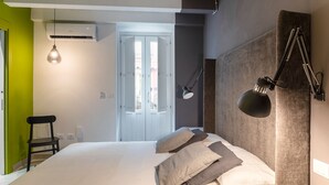A modern bedroom with a bed, bedside lamps, a shower, and a green wall. - Apartment (Siracusa)