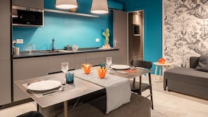 A modern kitchen with a blue accent wall, a built-in oven, and pendant lights. - Apartment (Siracusa)