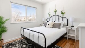 Une chambre à coucher comprenant un lit, des tables de chevet, un ventilateur de plafond, une fenêtre et une vue sur l’extérieur.