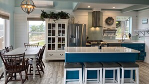 A modern kitchen with a central island, white cabinetry, and a blue accent wall. - Amazing views (Sequim)