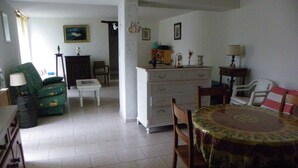 A dining area with a table, chairs, a sofa, and a small cabinet. - Studio (Canari)