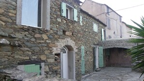 A stone building with a courtyard, featuring a central archway and multiple windows with shutters. - Studio (Canari)