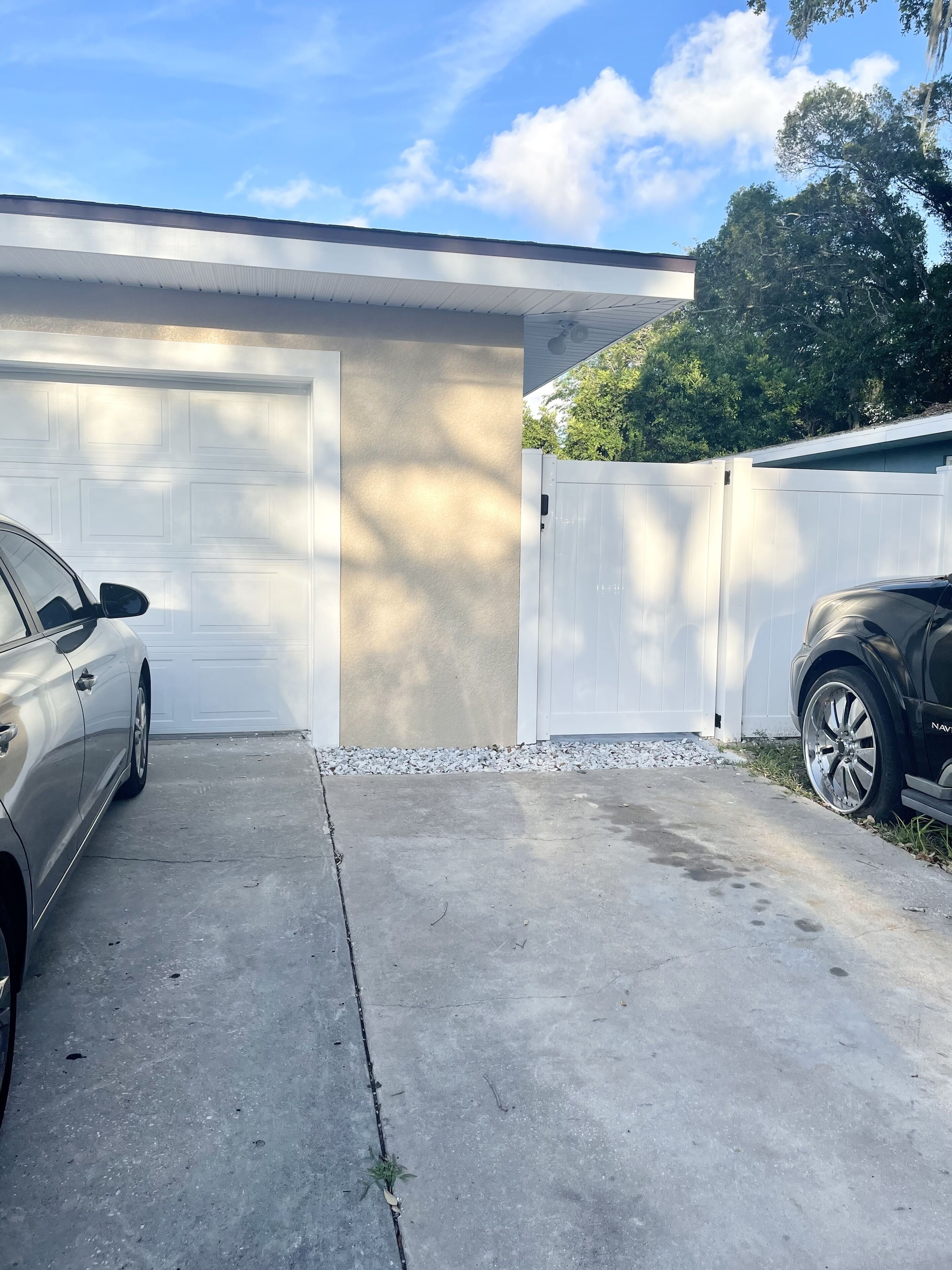 A garage with two cars parked, a concrete driveway, and a white garage door.