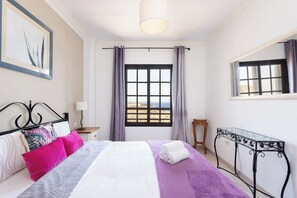 Een hotelkamer met een bed, een raam met gordijnen, een kleine tafel en een wandlamp.