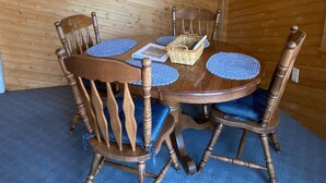 Puisesta ruokapöydästä, neljästä puisesta tuolista, seinäkellosta, kehystetyistä kuvista ja kyltistä, jossa lukee ”LAKE HOUSE”, koostuva ruokailutila.