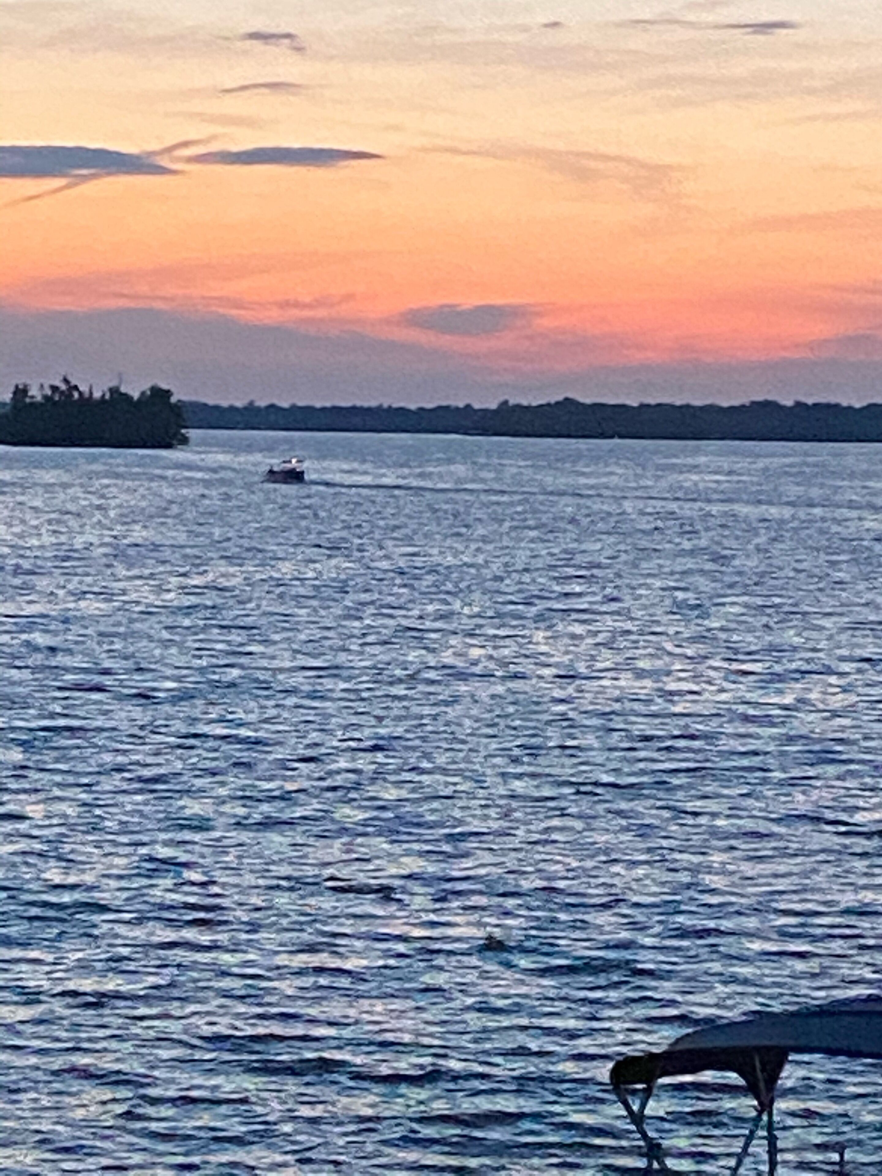A body of water with a boat and a distant landmass.