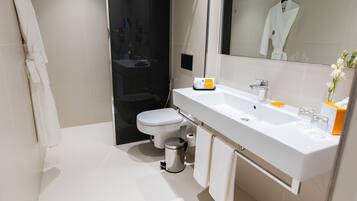 A modern bathroom with a white sink, mirror, and toilet.