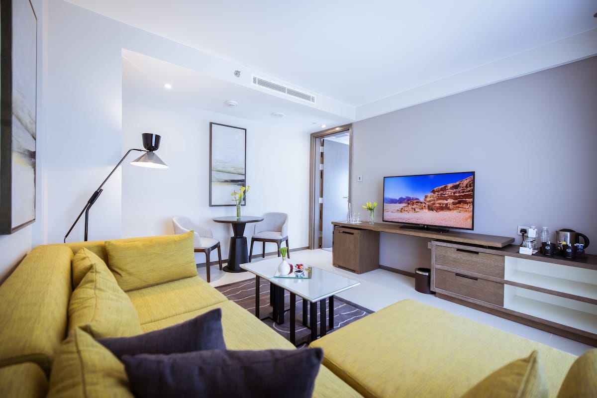 Un salon moderne comprenant un canapé, une table basse, un téléviseur et un coin repas avec des chaises et une table.