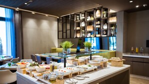A buffet setup with various food items and utensils, a glass-top table, and a modern interior with shelves and plants. - Centro Mada Amman By Rotana (Amman)