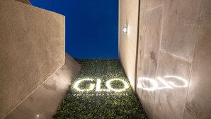 A modern interior with a 'GLO Rooftop Bar & Lounge' sign illuminated on a wall. - Centro Mada Amman By Rotana (Amman)
