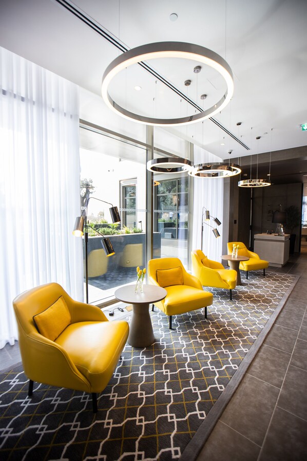 A modern hotel lobby with yellow armchairs, a round table, and a patterned floor. - Centro Mada Amman By Rotana (Amman)