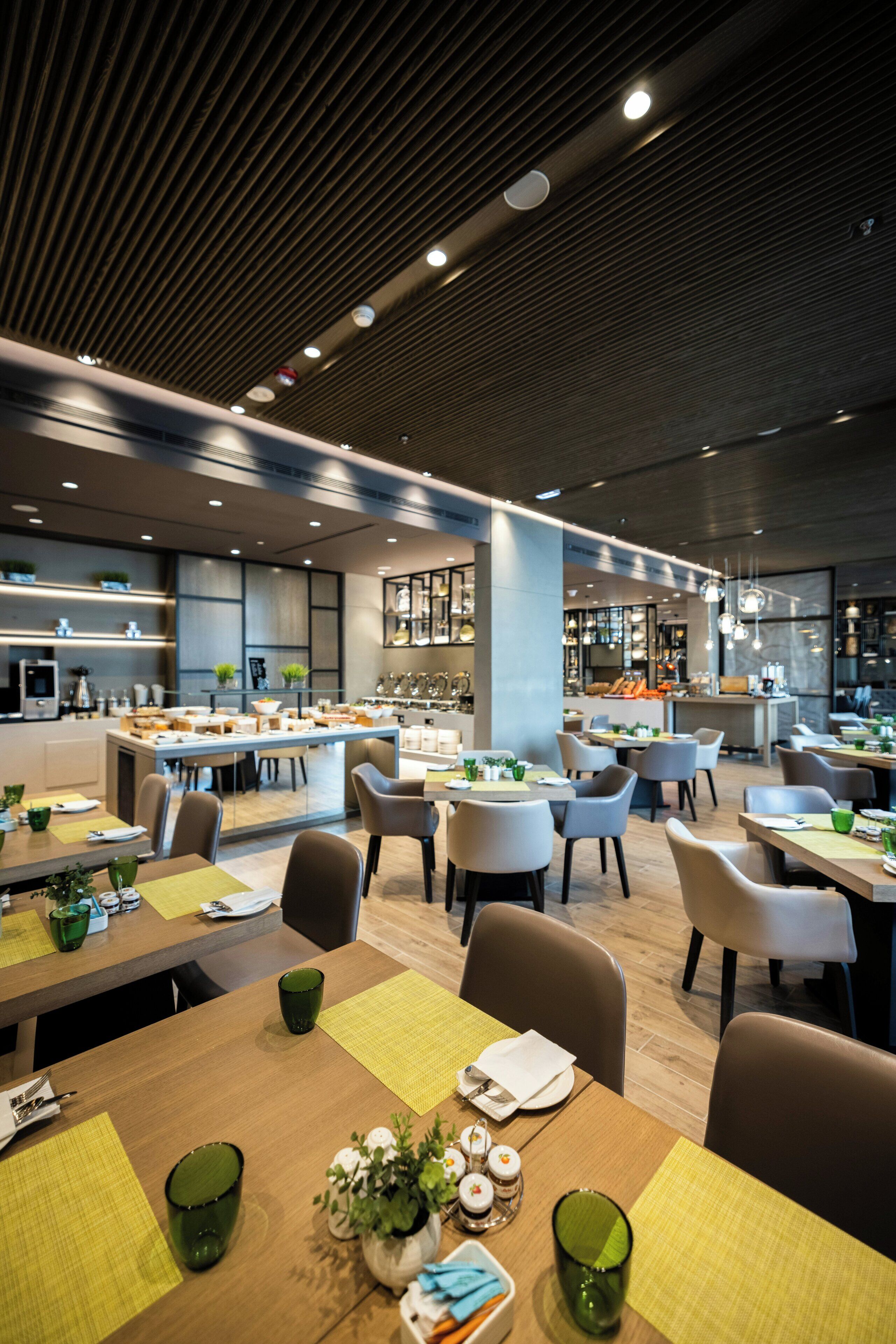 A modern restaurant with multiple dining areas, wooden tables, and chairs.