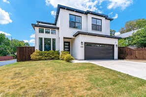 A modern two-story house with a garage, large windows, and a well-maintained lawn.