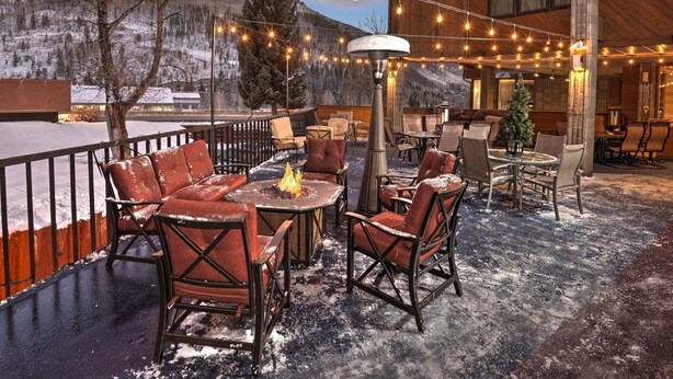 An outdoor seating area with leather chairs and a fire pit, overlooking a snowy mountain landscape. - Vail Run Resort for Christmas Break (Vail)