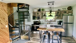 Une cuisine moderne avec un escalier en bois, des appareils électroménagers intégrés et un coin bar.