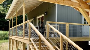 Une terrasse en bois avec un escalier menant à une zone abritée, le tout entouré d’une clôture en métal.