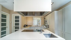 A modern kitchen with a large island, white cabinetry, and a built-in oven. - Magnificent villa a few steps from Playa de Muro (Alcúdia)