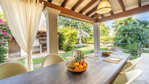 An outdoor patio with a wooden table, chairs, and a fruit bowl. - Magnificent villa a few steps from Playa de Muro (Alcúdia)