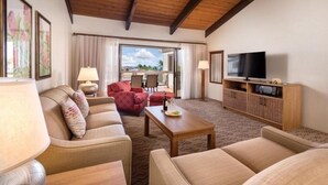 Une chambre d’hôtel avec un plafond en bois, un ensemble de meubles de salon, une télévision et une vue sur l’extérieur.