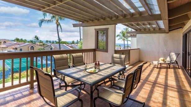 Une terrasse extérieure couverte, dotée d’une table et de chaises, qui offre une vue sur une piscine et des immeubles d’habitation.