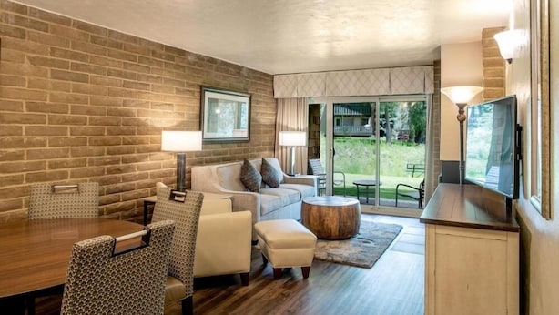 A modern living room with a brick wall, a sofa, a coffee table, and a TV.