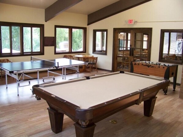 Une salle de billard équipée d’une table de billard, d’un baby-foot et d’une table de ping-pong.