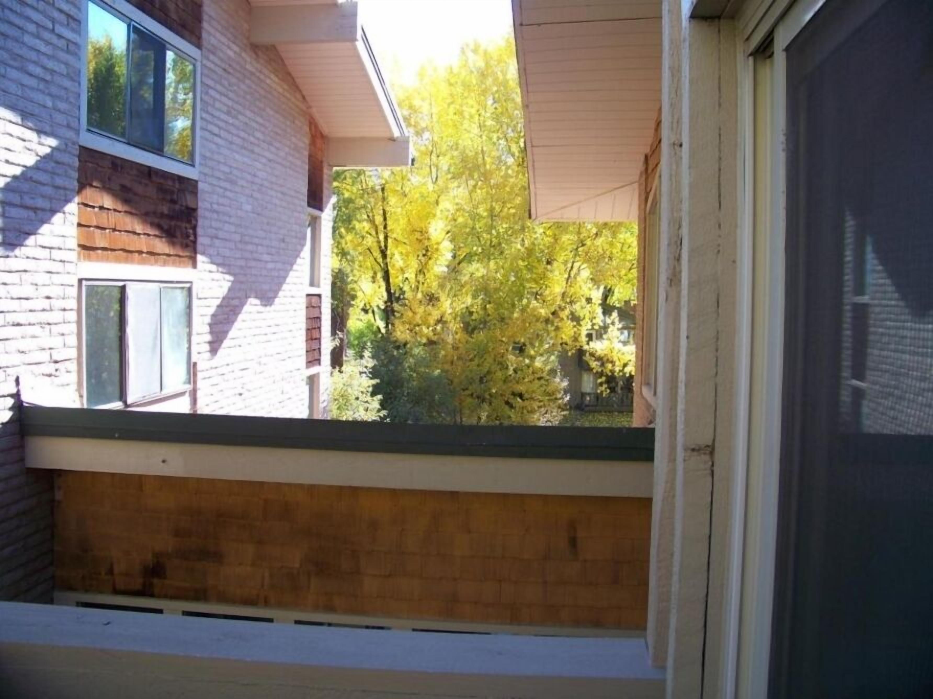 A view from a window overlooking a brick building with a wooden deck.