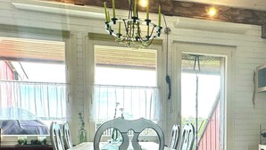 A dining area with a wooden table and chairs, a chandelier, and large windows. - Studio with kitchen, fireplace, terrace, barbecue - dogs allowed - Hohes Venn - Eifel (Monschau)