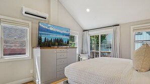 Un dormitorio con una cama grande, un aparador, un aire acondicionado y un cuadro de un paisaje montañoso.