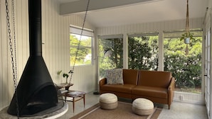 A cozy living room with a large fireplace, a brown leather sofa, and a view of greenery outside. - Amazing heated pool & spa just minutes from Anna Maria Island (Bradenton)