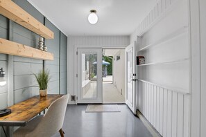 A hallway with a wooden table, a chair, a potted plant, and a door leading to an outdoor area. - Amazing heated pool & spa just minutes from Anna Maria Island (Bradenton)
