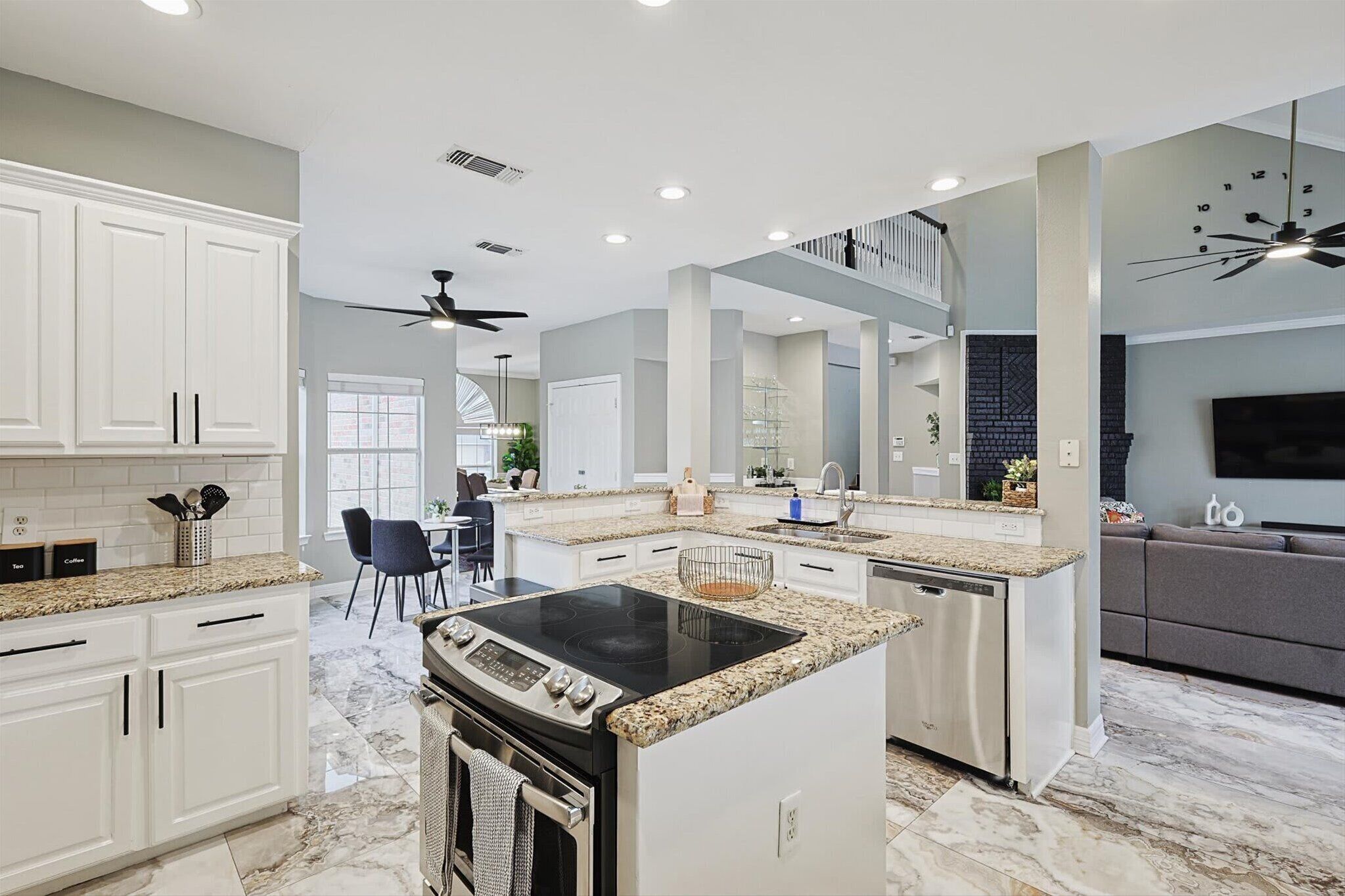 A modern kitchen with granite countertops, white cabinetry, and a central island with a stovetop.