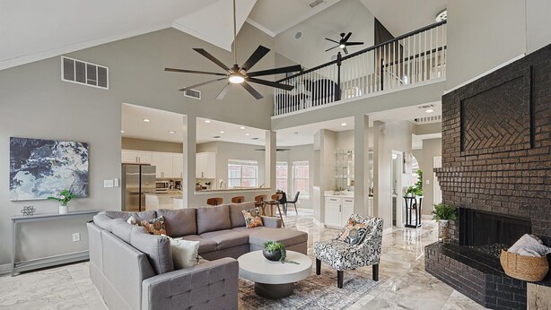 A spacious living area with a gray sectional sofa, a patterned armchair, a round coffee table, and a fireplace. - Immaculate 5BR/2.5B vila with Pool and cinema (Irving)