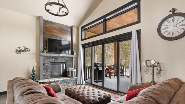 A living room with a fireplace, a large window, and a clock on the wall.
