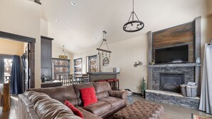 A spacious living room with a leather sofa, ottoman, and a fireplace.