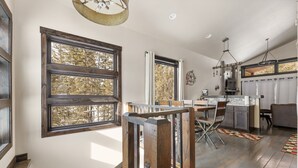 A spacious kitchen with large windows, a dining area, and a staircase leading to an upper level.