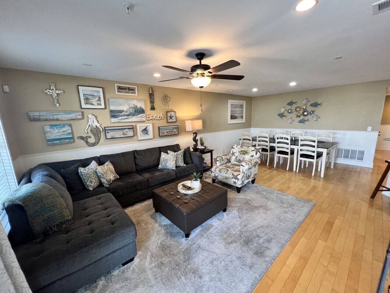 A living room with a dark brown sofa, a coffee table, and a dining area with white chairs and a table.