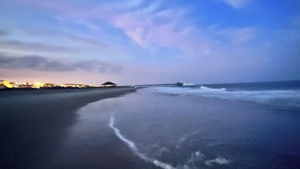 A beach with a calm sea, a pier in the distance, and a clear sky. - Tybee Retreat Unit 3 (Tybee Island)