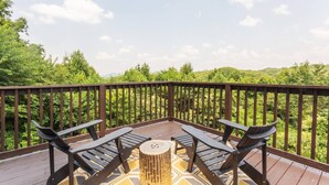 A wooden deck with a table and chairs, surrounded by a wooden railing, overlooking a lush green landscape. - ACID WASH @ DOLLYS DRIVE * Wifi Grill Woods Mtns (Sevierville)